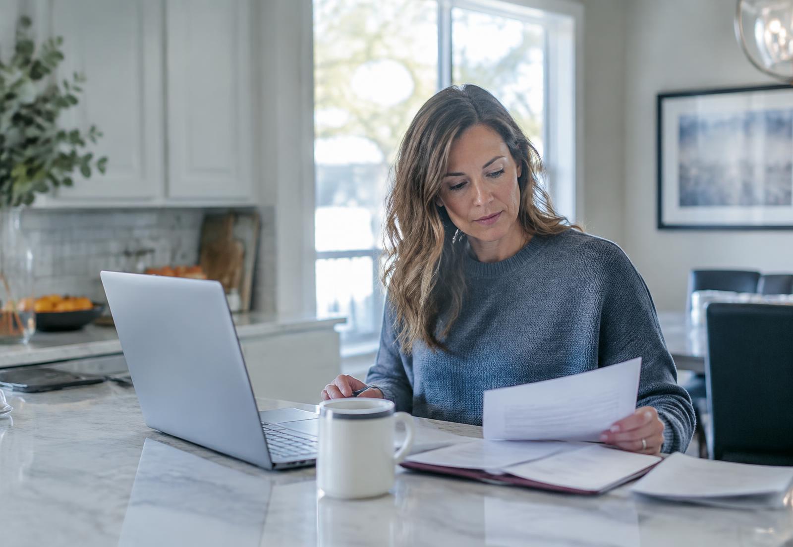 Homeowner reviewing mortgage paperwork at her kitchen island